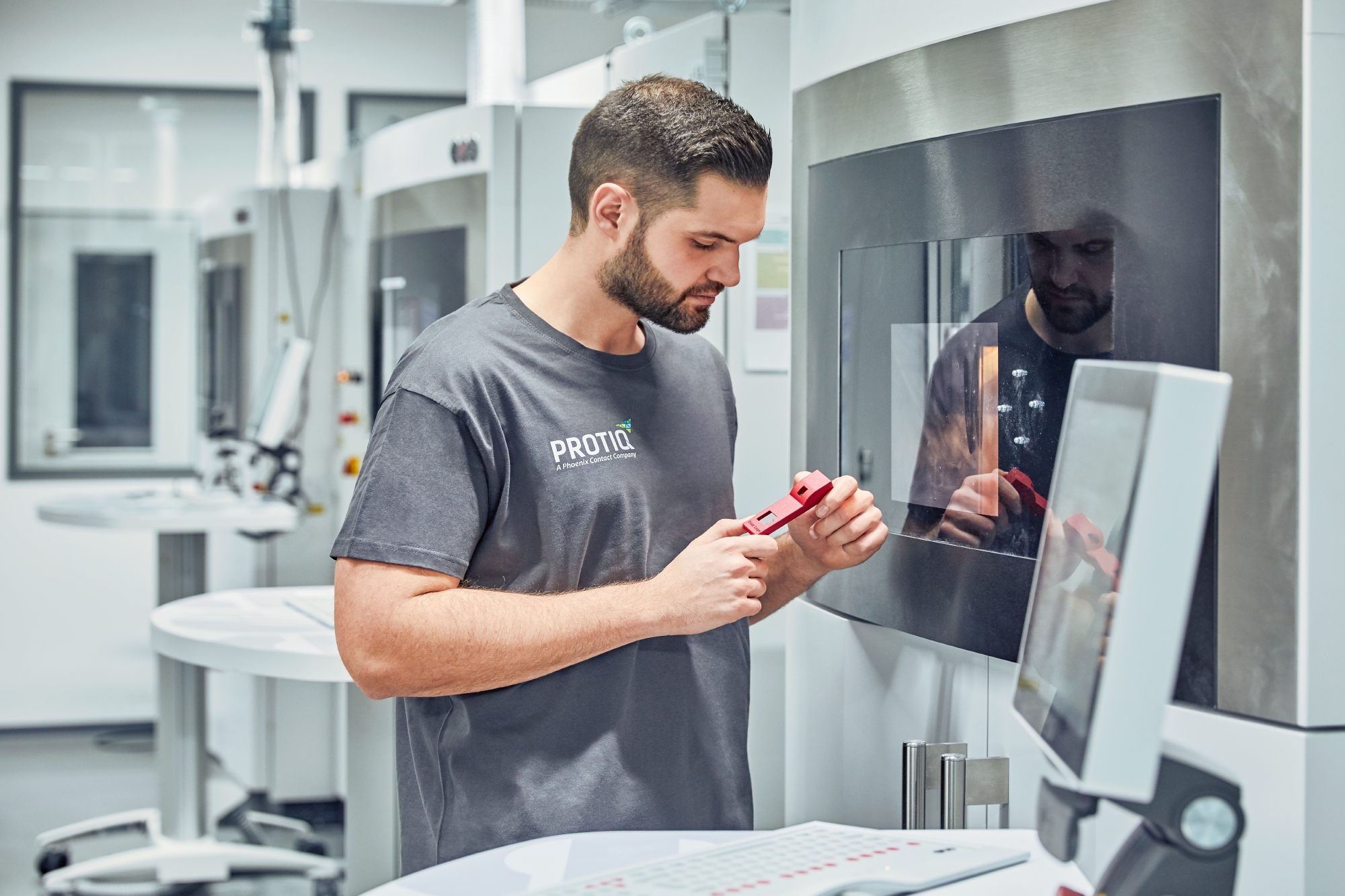 A man stands in front of a 3D printer and misses a component